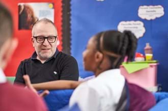 adult male counsellor talking to a young pupil in a classroom