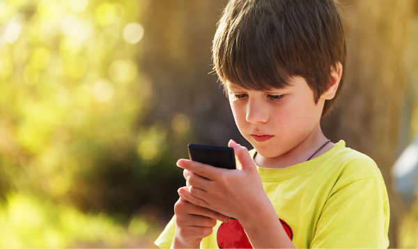 Child outside looking at smart phone