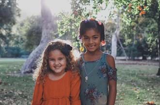 Two young girls standing in a garden smiling at camera