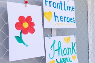 Artwork stuck to a window - a drawing of a flower, a drawing that says 'frontline heroes' and another that says 'thank you'