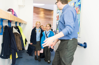 male teacher leading pupils into classroom