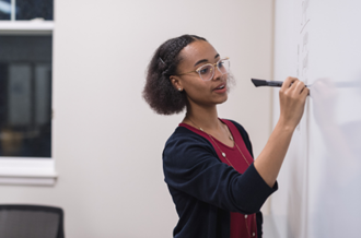 Young woman writes on whiteboard 