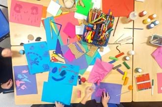 bird's-eye view of classroom table covered in colourful arts supplies