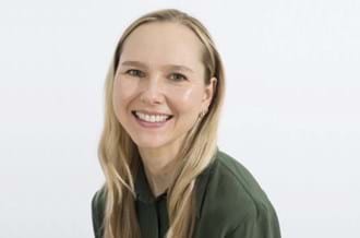 Headshot of Daria Bukhman, wearing a green top and sitting against a plain background