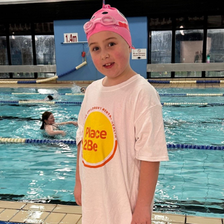 young girl next to swimming pool, wearing a Place2Be T-shirt
