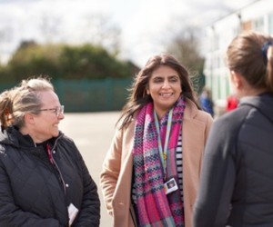 A group of school staff standing in a school playground together, talking to each other