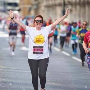marathon runner wearing Place2Be t shirt with arms up in air