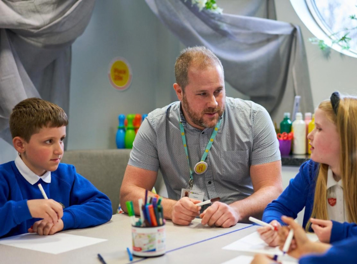 A Place2Be school counsellor speaking with school children who are drawing