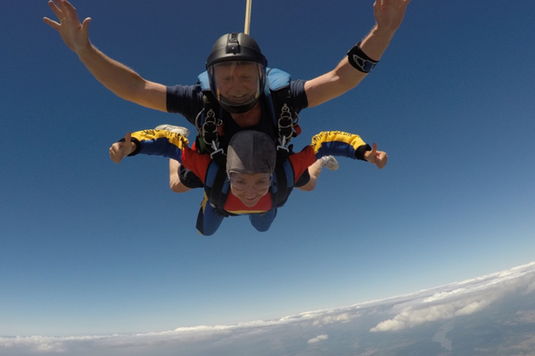 Andrea skydiving with instructor above the clouds!