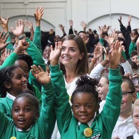 Jenna Coleman with students with arms waving at a Place2Be school