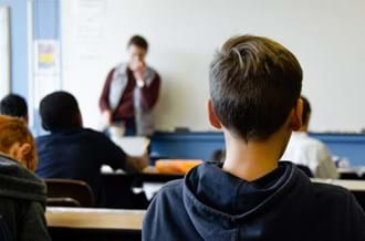 school pupil sitting in at classroom desk