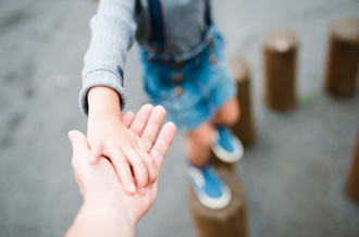 Child holding adult hand whilst playing