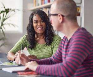 Two adults sitting at a table talking and smiling