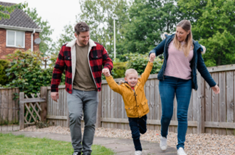 Mother, father and son walking outside house