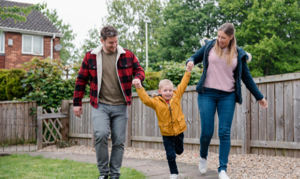 family (mother, father and child) walking outside a house