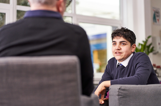 Smiling male teenager speaking to counsellor