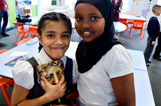 Two pupils holding a BAFTA award