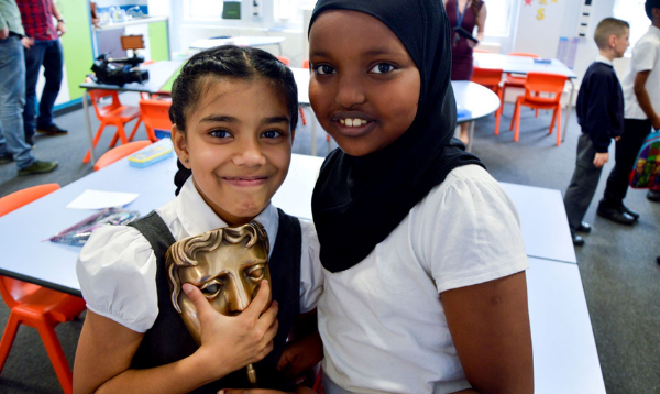Two female pupils holding a BAFTA award