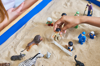 Hands playing with toys in sandbox