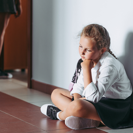 Girl in school uniform looking pensive in corridor