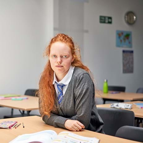 School girl sitting at desk looking into camera