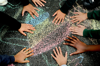 Children's hands touching chalk drawing of heart on playground