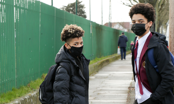 Two schoolboys wearing face coverings outside the school gates