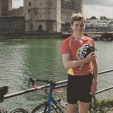 Fundraiser, Hugo, holding his cycling helmet next to his bike