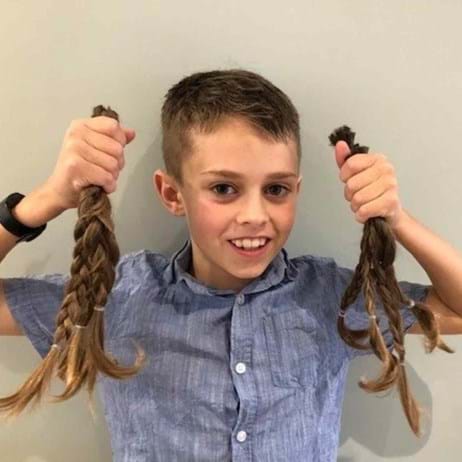 young boy holding the hair he grew out and then cut to raise money for Place2Be
