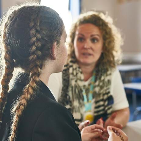 Young person and counsellor chatting in a classroom