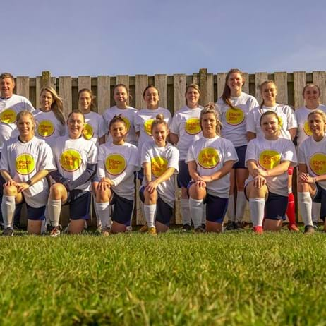 A sports team kneeling and standing, wearing Place2Be T-shirts