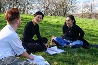 three people sat on grass in park