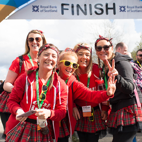 Group of women smiling under Kiltwalk finish banner