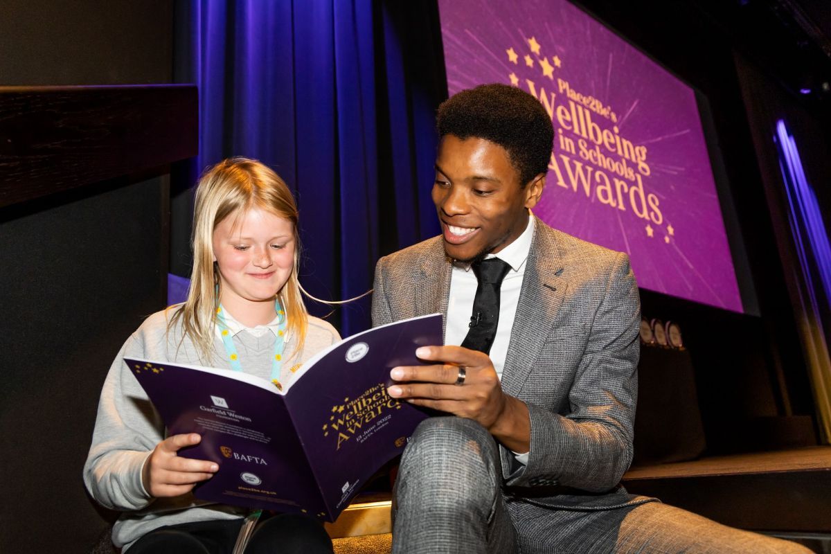 Place2Be ambassador Rhys reading with a child at the Wellbeing in Schools Awards.
