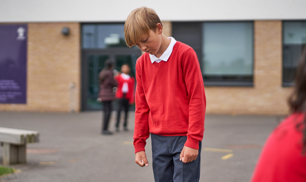 Boy in school playground looking frustrated