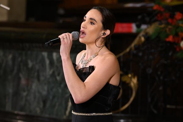 Laura Wright singing at Place2Be's carol concert. She is holding a microphone and looking at the crowd.