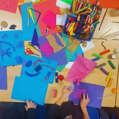 bird's-eye view of classroom table covered in colourful art materials