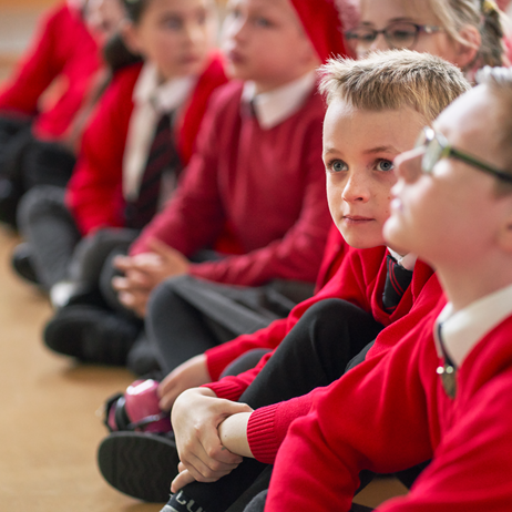 primary school children sitting on floor in school hall