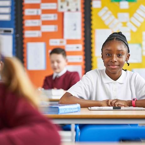 Young girl sat in a classroom smiling