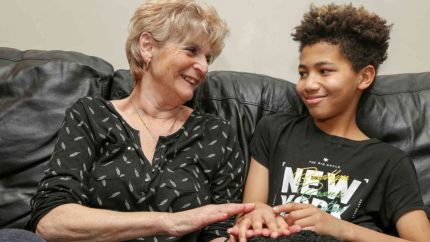 A woman and a boy sat on a sofa smiling at each other