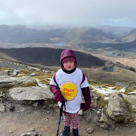 young girl in Place2Be T-shirt standing on a mountain