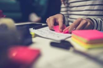 teacher sat at desk organising post-it notes