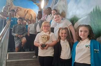 Pupils from Scotland school standing on a staircase all smiling at the camera. They benefitted from a Young BAFTA School visit and are holding a BAFTA award replica.
