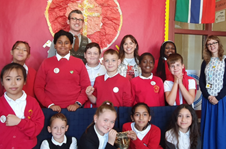 Students from St John Vianney RC Primary standing on school grounds with presenters Ben Shires and Robyn Richford (centre), alongside Place2Be School Project Manager Veronika Medne.