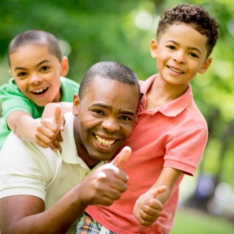 Father and 2 sons laughing and giving thumbs up