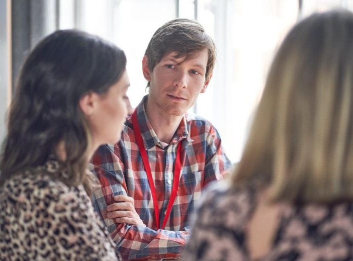 A group of 3 adults in a training session. They are talking together in a discussion.