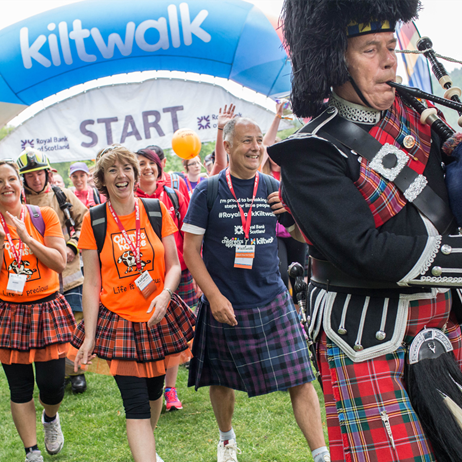 Bagpiper playing with group walking behind