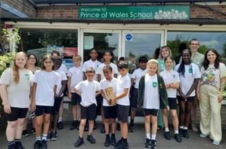 A class of students standing outside their classroom holding a BAFTA award with special talents