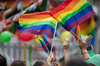 Two people waving rainbow Pride flags at a Pride march