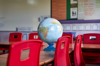 globe on desk in empty classroom